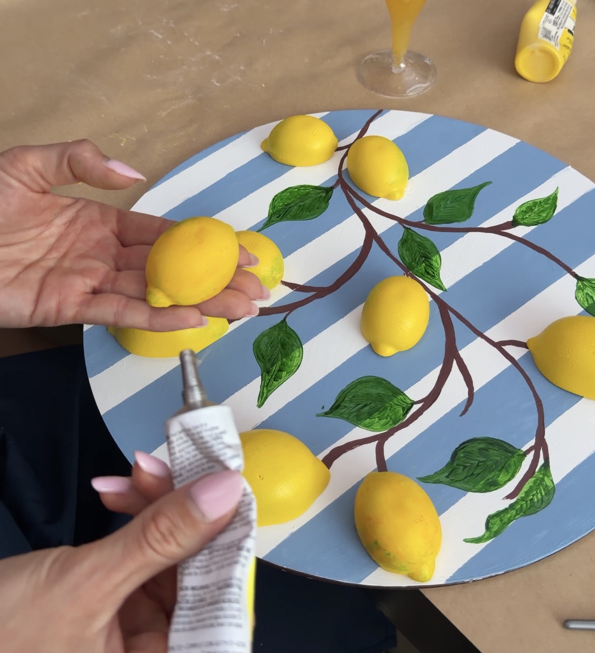 Hands adding dimensional lemons to painted artwork