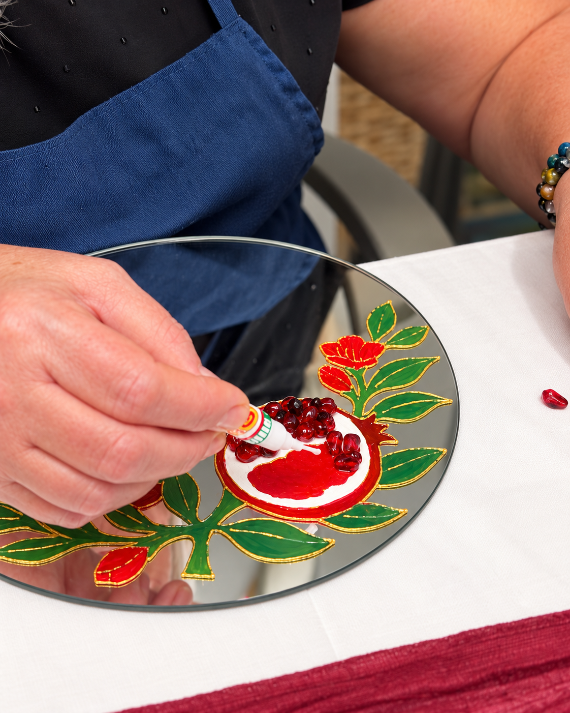 Attaching ruby-colored resin seeds to the painted pomegranate